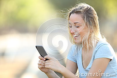 Happy teenage girl checking phone content in a park Stock Photo