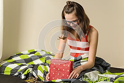 Happy teenage girl with a gift box at home sitting in bed Stock Photo