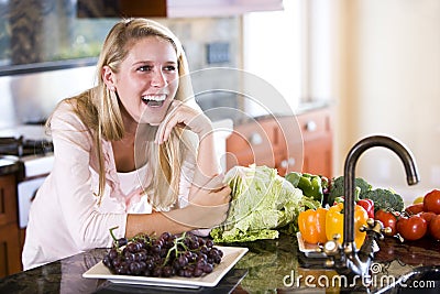 Happy teenage girl laughing in kitchen leaning on Stock Photo