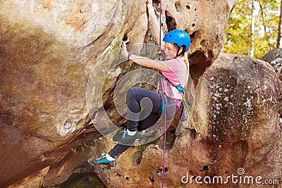Happy teenage girl rock climbing in forest area Stock Photo