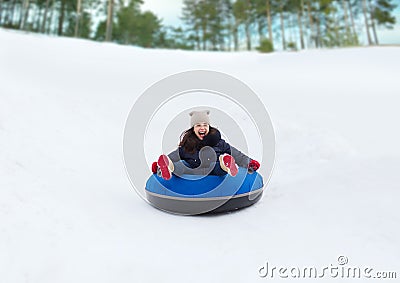 Happy teenage girl sliding down on snow tube Stock Photo