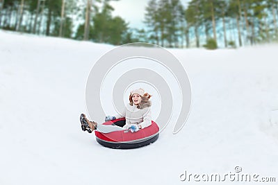 Happy teenage girl sliding down on snow tube Stock Photo