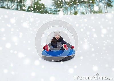 Happy teenage girl sliding down on snow tube Stock Photo