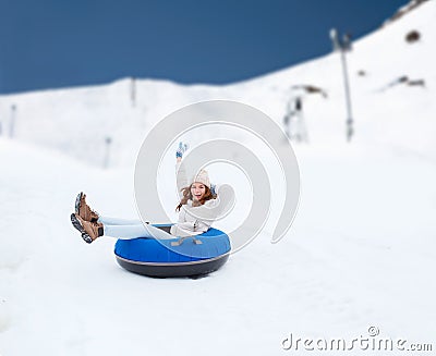 Happy teenage girl sliding down on snow tube Stock Photo