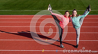 Happy teenage gymnasts do vertical splits holding legs at athletics track, copy space, gymnastics Stock Photo