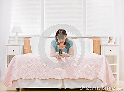 Happy teenager laying on bed text messaging Stock Photo