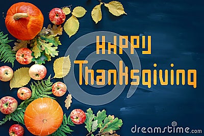 Happy Thanksgiving text with pumpkins and leaves over dark wood background Stock Photo