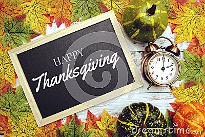 Happy Thanksgiving text on blackboard decorate with maple leaves and pumpkin on wooden background Stock Photo