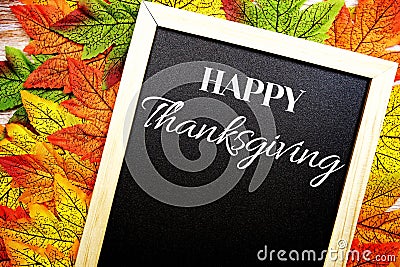 Happy Thanksgiving text on blackboard decorate with maple leaves and pumpkin on wooden background Stock Photo