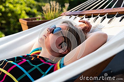 Happy thirty year old woman wearing colorful summer clothes lying in a hammock Stock Photo