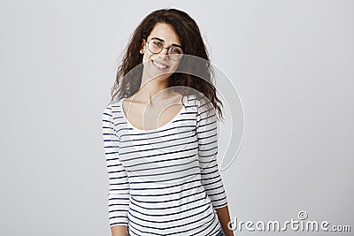 Happy to be in crowd of friends. Portrait of pleased charming curly-haired daughter in glasses smiling cheerfully Stock Photo