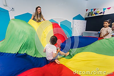 Happy toddlers having an active sensory play with texture and colors at the nursery school. Kids wellness. Early fine Stock Photo