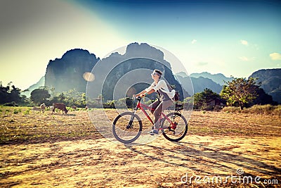 Happy tourist woman riding a bicycle in mountain area in Laos. T Stock Photo