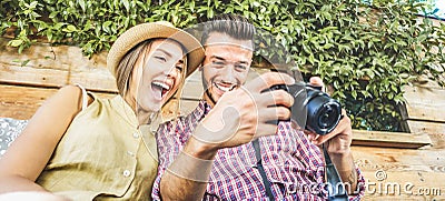 Happy travel couple watching photos on mirrorless camera - Young people having fun on summer vacation - Main focus on him - Stock Photo