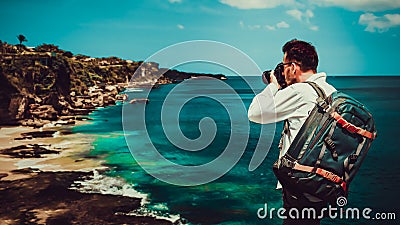 Traveller man backpacker standing on the top mountain cliff on background tropical beach Stock Photo