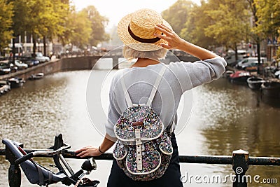 Happy traveler girl enjoying Amsterdam city. Tourist woman looking to the Amsterdam canal, Netherlands, Europe Stock Photo