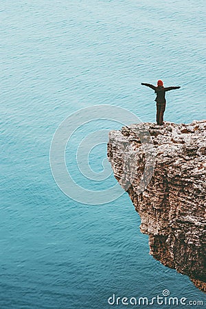 Happy traveler standing on cliff above sea hands raised Travel Lifestyle success motivation concept Stock Photo