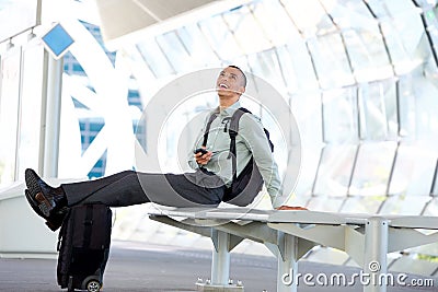 Happy traveling businessman waiting at station with his bags and mobile phone Stock Photo