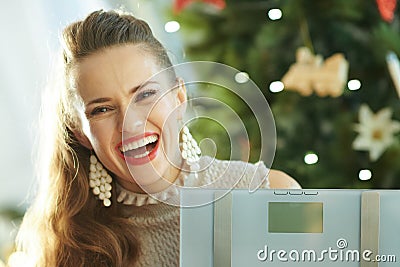 Trendy woman near Christmas tree showing weight scales Stock Photo