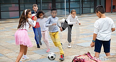 Happy tween girls and boys playing football in schoolyard Stock Photo