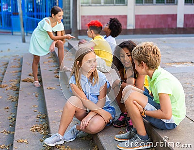 Happy tweenagers friends sitting on steps outdoors and chatting Stock Photo