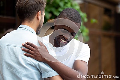 Happy two multiracial male best friends greeting embracing at meeting Stock Photo