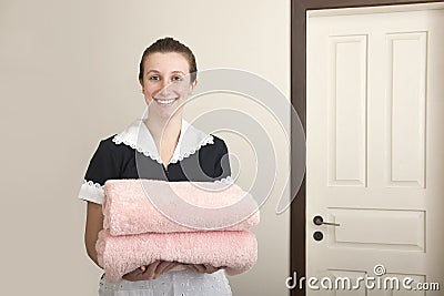 Happy uniformed maid with towels Stock Photo