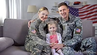 Happy US military family hugging on sofa smiling at camera nation and patriotism Stock Photo