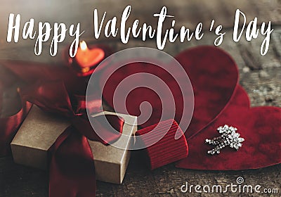 Happy Valentine`s day text on gift box, luxury earrings and red velvet hearts on rustic wood. Card Stock Photo