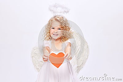 Happy Valentine& x27;s Day. Little baby cupid, beautiful girl in white dress holding paper heart isolated over white Stock Photo