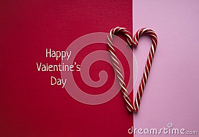 Happy Valentines Day banner with sweet striped candy canes in heart shape on red and pink background Stock Photo