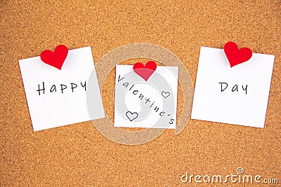 Happy valentines day lettering on white paper fastened with 3 felt heart pushpin on cork board Stock Photo