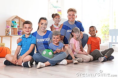 Happy volunteers with children sitting on floor Stock Photo