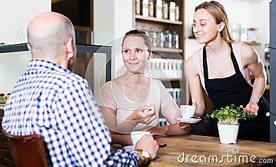 happy waiter girl brought cup of coffee for couple of different aged people Stock Photo