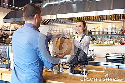 Happy waitress waring apron serving customer at counter in small family eatery restaurant Stock Photo