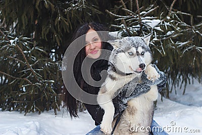 Happy winter time of joyful young woman playing with cute husky dog in snow on street. Stock Photo