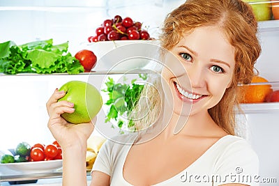 Happy woman with apple and open refrigerator with fruits, vegeta Stock Photo