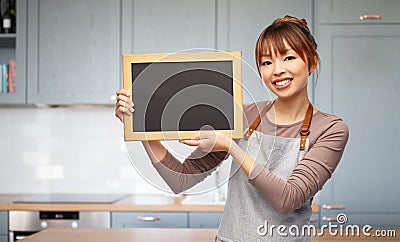 happy woman in apron with chalkboard in kitchen Stock Photo