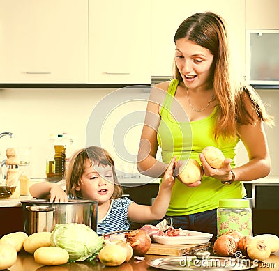 Happy woman with baby cooking with potatoes Stock Photo