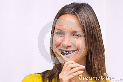 Happy woman brushing teeth with bamboo toothbrush with black charcoal toothpaste Stock Photo