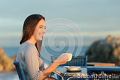 Happy woman contemplating in a coffee shop on the beach Stock Photo