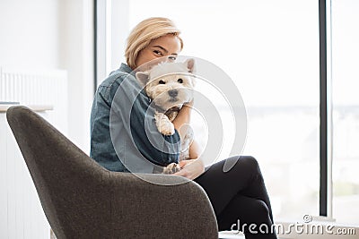 Happy woman cuddling furry pet with closed eyes at home Stock Photo