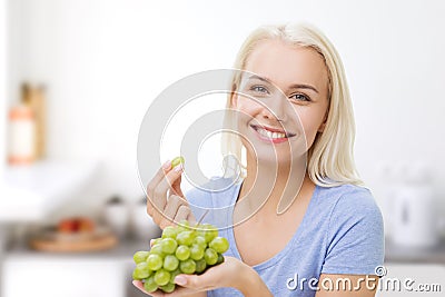 Happy woman eating grapes on kitchen Stock Photo