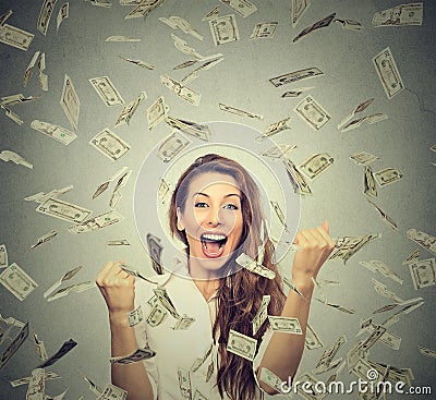 Happy woman exults pumping fists ecstatic celebrates success under a money rain Stock Photo