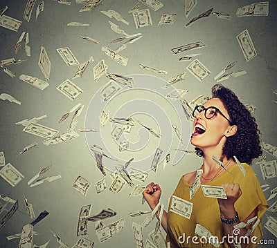 Happy woman exults pumping fists ecstatic celebrates success under a money rain Stock Photo