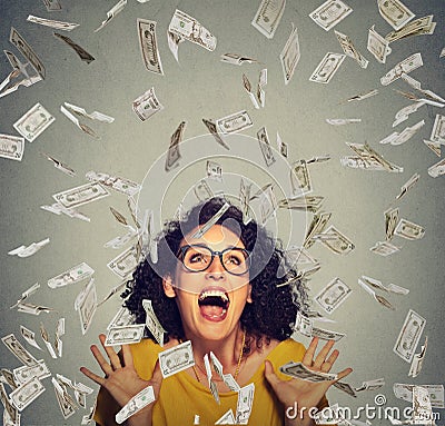 Happy woman exults pumping fists ecstatic celebrates success under a money rain Stock Photo