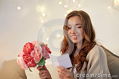 Happy woman with flowers and greeting card at home Stock Photo