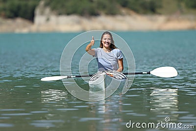 Happy woman gesturing thumb up in a kayak in a lake Stock Photo