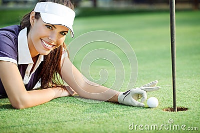 Happy woman golf pushing golf ball into the hole Stock Photo