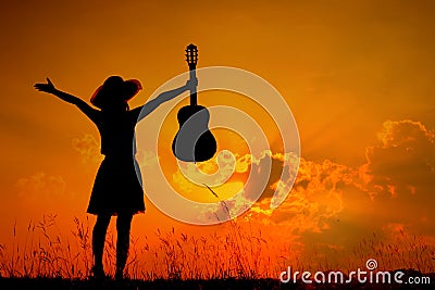 Happy Woman and guitar with sunset silhouette Stock Photo